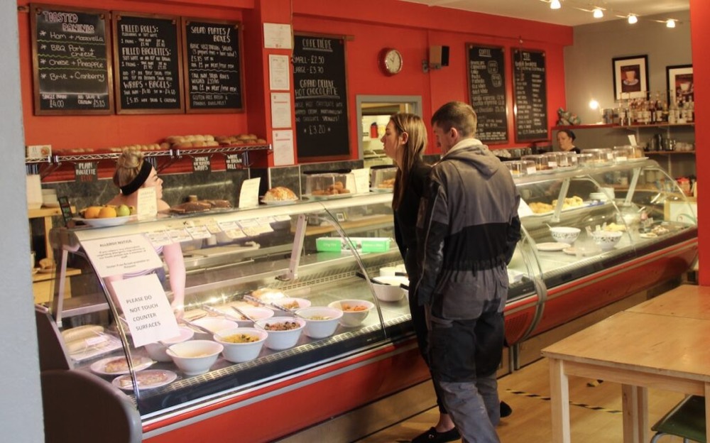 two people stand at counter in a cafe